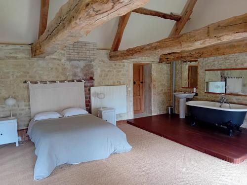 - une chambre avec un lit, une baignoire et un lavabo dans l'établissement Magnifique château rénové proche bourg grand parc belle terrasse billard, ping pong, proche Bayeux et plages du débarquement, à Tilly-sur-Seulles