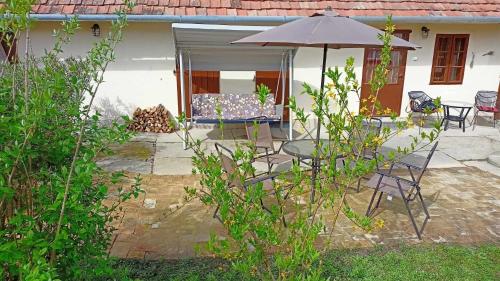 a patio with a table and chairs and an umbrella at Neubauer Vendégház*** Mohács in Mohács