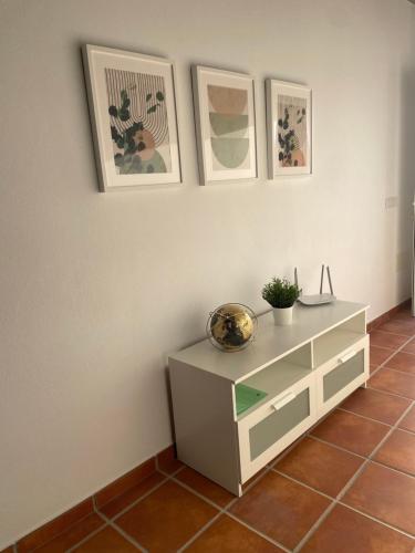 a white cabinet with three pictures on the wall at Apartamento en Mala Las Mercedes in Mala