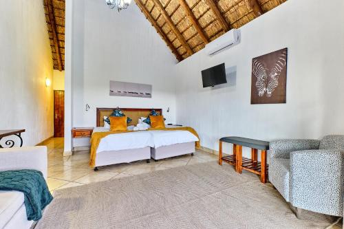 a bedroom with two beds and a tv and a couch at Shasha Lodge, Mabalingwe Game Reserve in Mabula