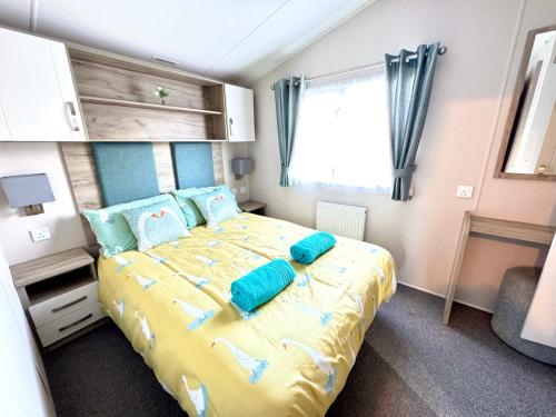 a bedroom with a large bed with blue pillows at Drakes View Dog friendly chalet in South Cerney