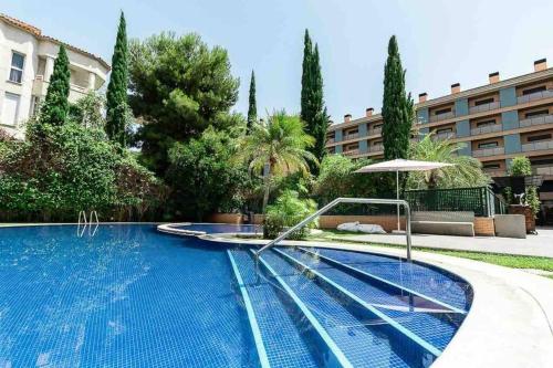 a swimming pool with an umbrella and a building at Ibo beach apartment Albir in Albir