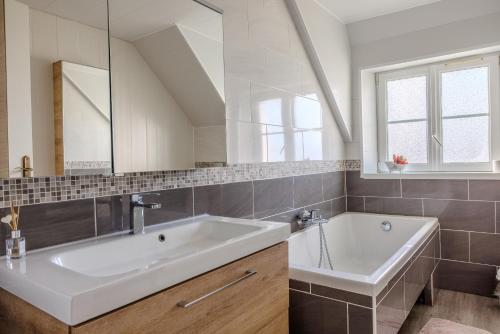 ein weißes Badezimmer mit einer Badewanne und einem Waschbecken in der Unterkunft ARVEIL in Plomeur