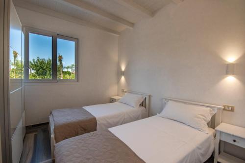 two beds in a room with two windows at Villa del Papiro Charme Apartments in Avola