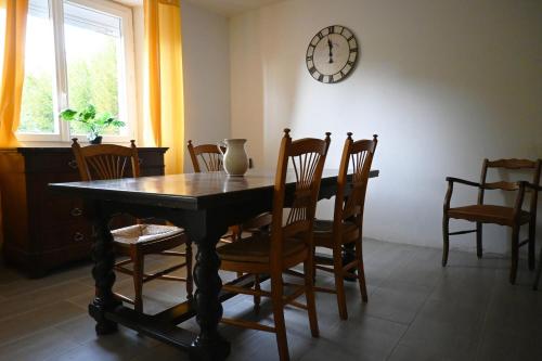 een eettafel met stoelen en een klok aan de muur bij Gîte du RELAI du Château - Parc Oriental - Puy du Fou in La Tourlandry