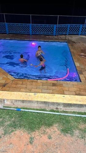 three people in a swimming pool at night at Igaratá Beach Casa em Igaratá Pé na água in Igaratá