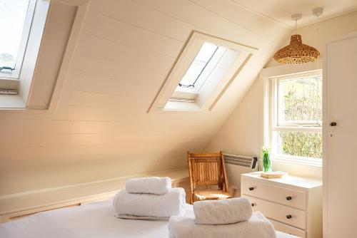 a attic bedroom with skylights and a bed and a chair at The Sail Loft (part of Manor House) in Port Isaac