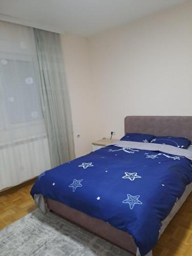a bed with a blue comforter with stars on it at Lovely Apartment with terrace/Divan apartman sa terasom in Novo Selo