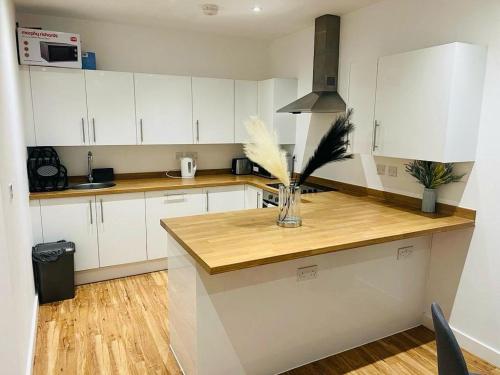 a kitchen with white cabinets and a vase of flowers on a counter at A Cosy 2bedroom Apartment With River View in Gillingham