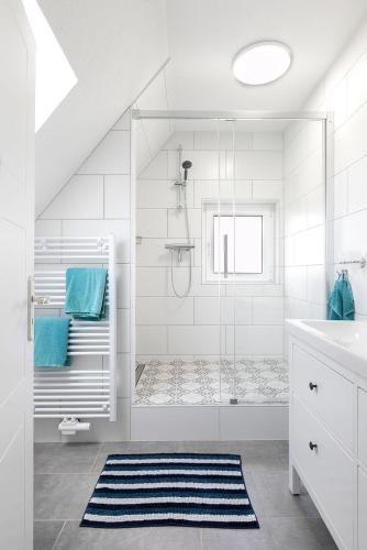 a white bathroom with a shower and a blue rug at Haus Delphin in Juist