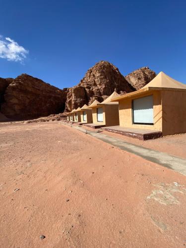 a building in the desert with mountains in the background at مخيم الانيق in Wadi Rum