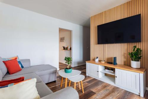a living room with a couch and a tv on a wall at Bela Vista Barrinha in Praia de Mira