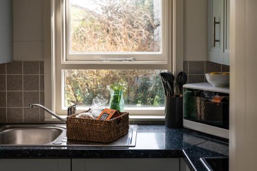 a kitchen counter with a sink and a window at The Sail Loft (part of Manor House) in Port Isaac