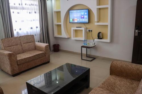 uma sala de estar com um sofá e uma televisão em BUNGOMA ROYAL SUITES em Bungoma