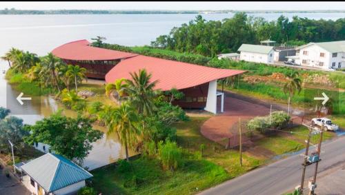 uma casa com um telhado vermelho ao lado da água em Ark of Reset em Paramaribo