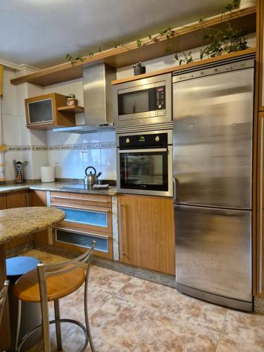 a kitchen with stainless steel appliances and a table at Adosado playa Rodeira in Cangas de Morrazo