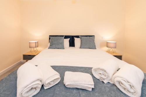 a bedroom with a large white bed with towels on it at 2 Bedroom Flat Free Parking in Reading