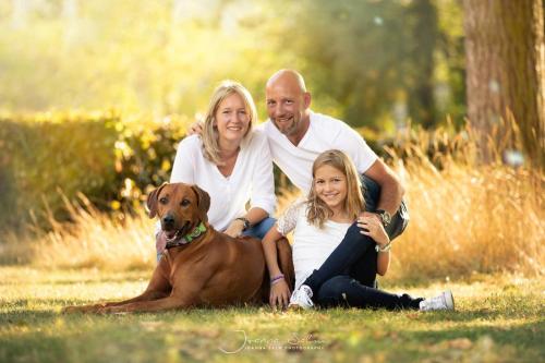uma família posando para uma foto com o seu cão em Alpin Apartments em Maria Alm am Steinernen Meer