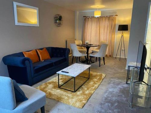 a living room with a blue couch and a table at BridgeCity Spacious Cottage in the Heart of Basingstoke in Worting