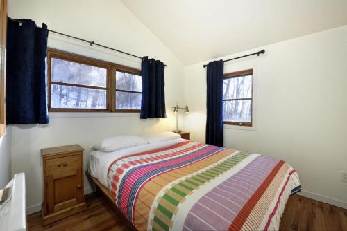 sypialnia z łóżkiem i 2 oknami w obiekcie Chalets Alpins -11 Chemin Alpin w mieście Stoneham