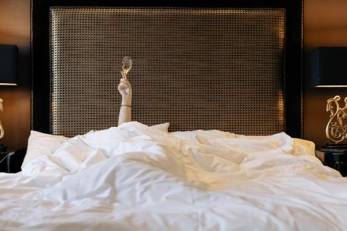a person laying in bed with a glass of wine at Vimmerby Stadshotell, WorldHotels Crafted in Vimmerby