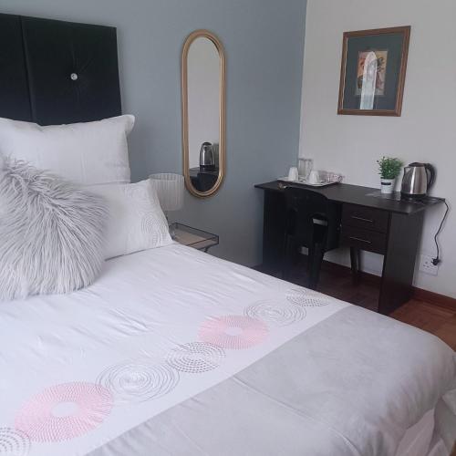 um quarto com uma cama e uma secretária com um espelho em MaThwala guesthouse em Vanderbijlpark