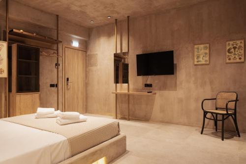 1 dormitorio con 1 cama, TV y silla en Medusa Luxury Suites, en Neos Marmaras