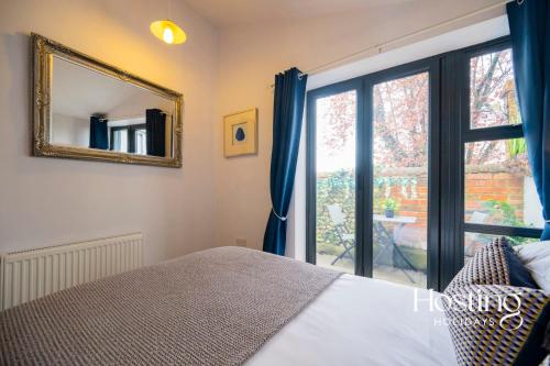 a bedroom with a bed and a mirror and a window at Greys View Cottage in Henley on Thames