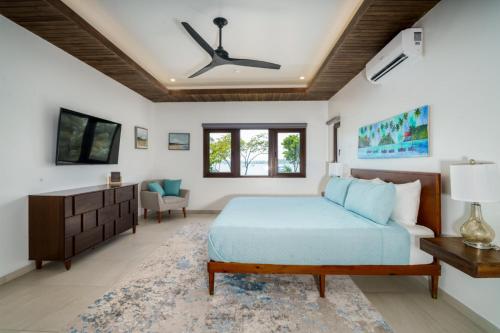 a bedroom with a bed and a ceiling fan at NEW Oceanfront 5 Bedroom Private Island Villa in Placencia Village