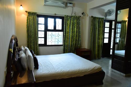 a bedroom with a bed and two windows with green curtains at Service Apartment in Richmond road in Bangalore