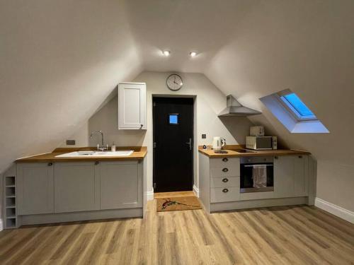 an attic kitchen with a sink and a clock at Roseberry View Barn, Northallerton in Northallerton