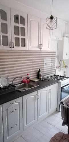 a white kitchen with white cabinets and a sink at Garsoniera Ghiță in Chiajna