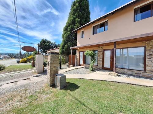 ein Haus mit einem Rasen davor in der Unterkunft Departamentos Serendipia Dina Huapi in Dina Huapi