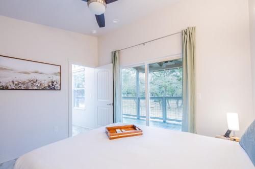 a white bedroom with a bed and a large window at Serene Hill Country Home w/ Romantic Garden Escape in Driftwood