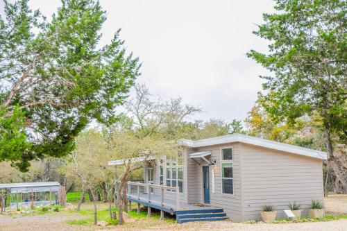 a small white tiny house with a porch at Serene Hill Country Home w/ Romantic Garden Escape in Driftwood