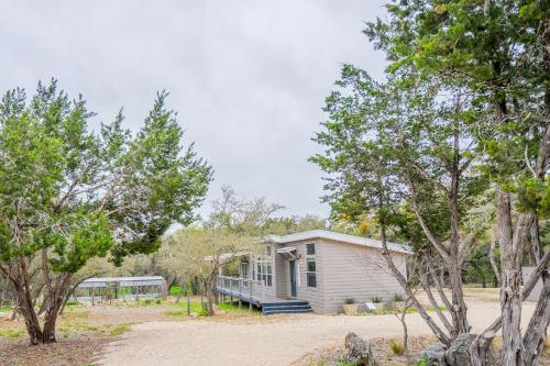a small white house with a porch and trees at Serene Hill Country Home w/ Romantic Garden Escape in Driftwood