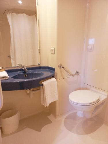 une salle de bain avec un lavabo bleu et des toilettes dans l'établissement ibis budget Saint-Brieuc Yffiniac, à Yffiniac