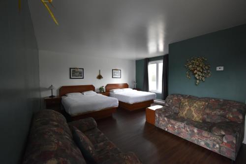 a living room with two beds and a couch at Motel ANF in Drummondville