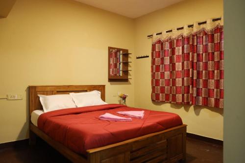 a bedroom with a bed with red sheets and a window at LA SIESTA in Ooty
