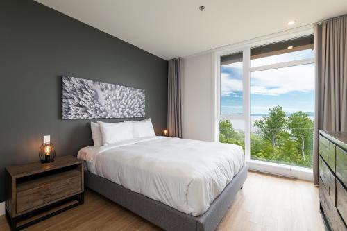um quarto com uma cama e uma grande janela em Les Appartements du Massif de Charlevoix em Petite-Rivière-Saint-François