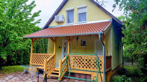 una pequeña casa amarilla con terraza y mesa en Strandközeli Babu-házunk kiadó!, en Velence