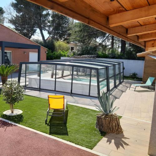 un pavillon en verre avec une chaise et une plante dans l'établissement Blue Maldives, à Argeliers