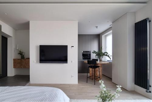 a bedroom with a white wall with a flat screen tv at E l e v e n in Ivano-Frankivsʼk
