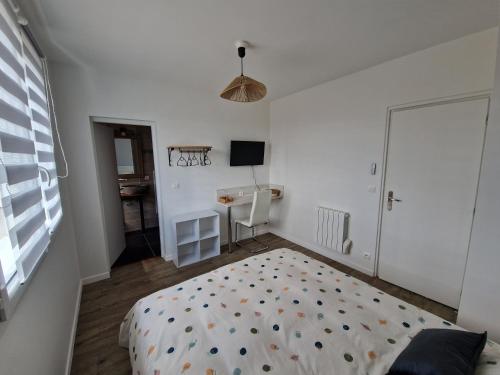 a bedroom with a bed and a desk and a television at Le Nid Cabailla in Coimères