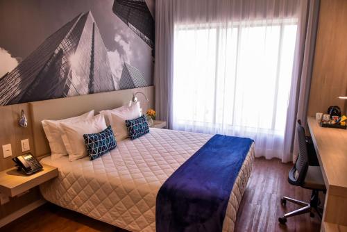 a bedroom with a bed and a desk and a window at Rio Hotel by Bourbon Sao Paulo in Sao Paulo