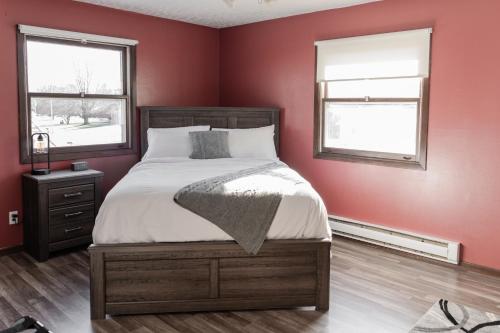 - une chambre avec un lit aux murs rouges et 2 fenêtres dans l'établissement The Hemlock/Hot Tub/Golf/Private Yard, à Spring Green