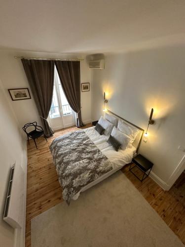 une chambre avec un grand lit et deux fenêtres dans l'établissement Appartement Eugénie, à Vichy