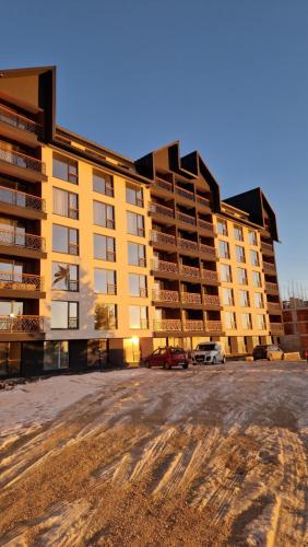 a large yellow building with cars parked in a parking lot at Marrilux apartments Residence Hill in Kopaonik