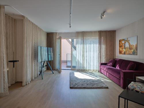 a living room with a purple couch and a tv at Haus Fünf mit 2 Apartments und Studio-Loft mit Terrasse in Melk