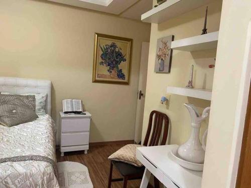 Schlafzimmer mit einem Bett und einem Schreibtisch mit einem Telefon in der Unterkunft Apartamento Encantador C in Montes Claros